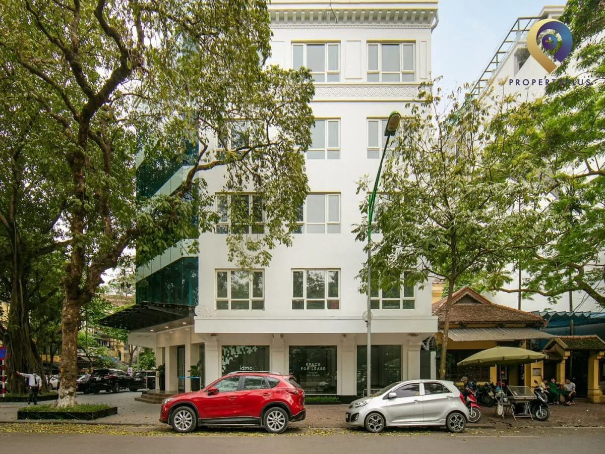 Tòa nhà IDMC-Hoàn-Kiếm nhìn từ phía trước với hàng cây xanh và xe cộ qua lại.